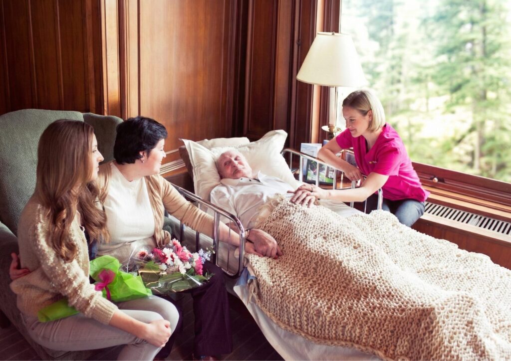 Support at Home End-of-Life Pathway 3 Elderly man in bed surrounded by his family and being cared for by Nurse Next Door Nurse 1