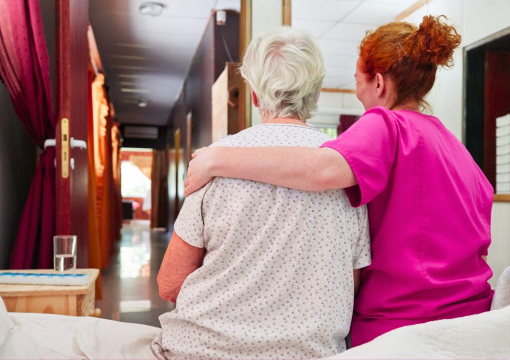 Support at Home End-of-Life Pathway 1 Elderly woman sitting up and being comforted by Nurse Next Door Nurse
