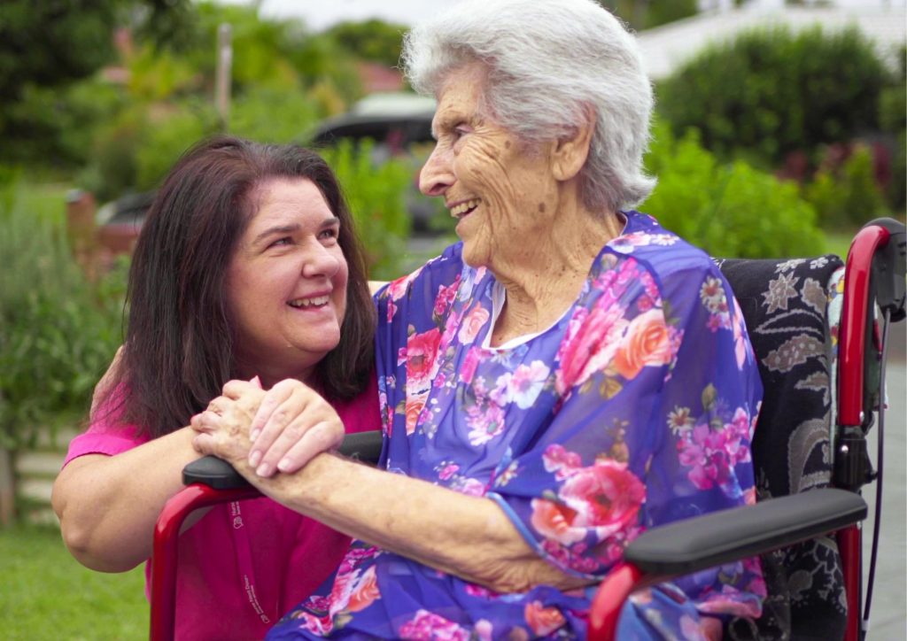 Caregiver with elderly client smiling together