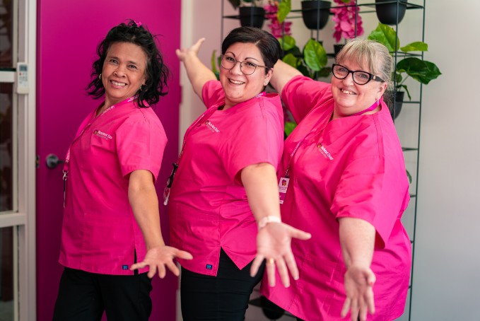 Three nurses in the office, smiling with their arms open 