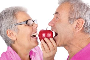 An older man and woman sharing an apple