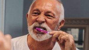 man brushing his teeth in the mirror