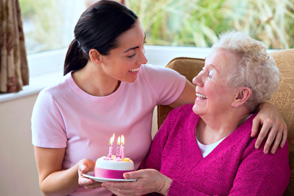 Elderly woman celebrating her birthday with her caregiver