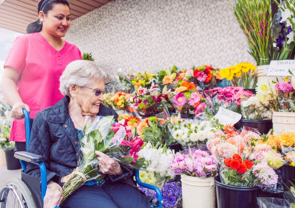 Senior Woman and Cargiver out in the community buying flowers