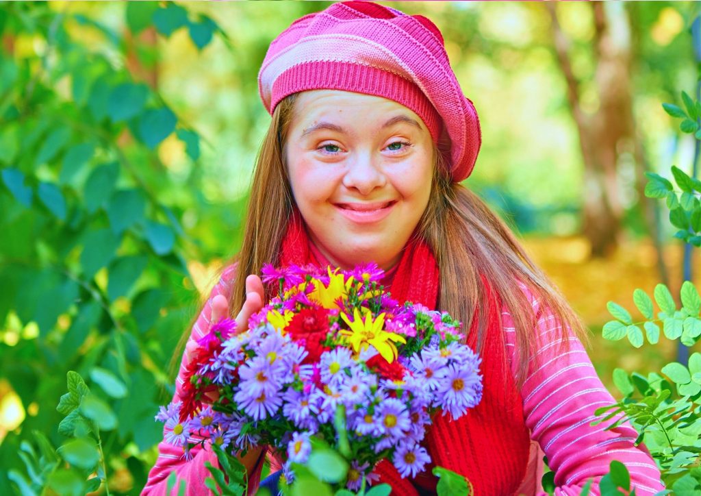Youn girl with Down Syndrome picking flowers and smiling