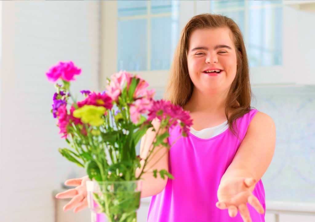 Young girl with Down Syndrome arranging pink flowers